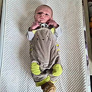 Viltys a rejoint le concours — aidez-le/la à gagner de superbes lots ! baby, infant, child, lying_down, clothing, onesie, animal_theme, yellow, socks, cute, textured_background, portrait, face, hands, feet, bed, soft, indoor, newborn, expression