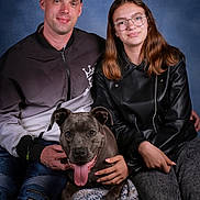 Grisouille a rejoint le concours — aidez-le/la à gagner de superbes lots ! animal, blue_background, cap, casual_clothing, dog, friendship, glasses, happy, indoor, jeans, knitted_blanket, leather_jacket, man, people, pet, portrait, sitting, smiling, studio, woman