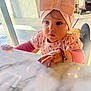 Maddison is registered to the contest to win money with this photo: toddler, child, girl, headband, pink, bow, table, marble, indoor, sunlight, window, curious, clothing, bracelet, hand, face, expression, earring, chair, baby