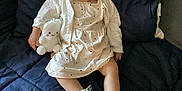 Maddison joined the competition — help win amazing prizes! toddler, child, flower_crown, white_dress, plush_toy, socks, couch, remote_control, home, indoor, cute, sitting, clothing, accessory, face, person, furniture, soft_toy, decor, expression