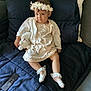 toddler, child, flower_crown, white_dress, plush_toy, socks, couch, remote_control, home, indoor, cute, sitting, clothing, accessory, face, person, furniture, soft_toy, decor, expression