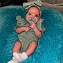 baby, infant, pacifier, headband, green_outfit, socks, plush_cushion, blue_cushion, indoor, cute, child, young_baby, comfortable, relaxed, person, portrait, small_hands, small_feet, resting, cozy