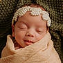 newborn, baby, sleeping, pearl_headband, blanket, wrapped, closeup, portrait, infant, soft_texture, knitted_background, peaceful, cute, head, face, skin, indoors, resting, calm, child