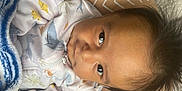 Greyson joined the competition — help win amazing prizes! baby, infant, face, eyes, hair, clothing, onesie, blanket, pattern, cushion, indoor, person, cute, sleepwear, child, lying_down, expression, closeup, young, soft