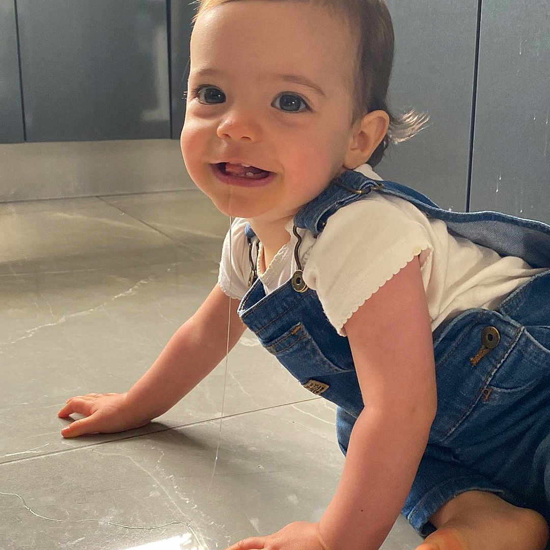 Isabella participe au concours pour gagner de l'argent avec cette photo : baby, child, crawling, cute, denim_overalls, face, floor, foot, hand, happy, indoor, kitchen, light, modern, person, reflection, smiling, tile_floor, toddler, white_shirt