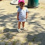 Emma participe au concours pour gagner de l'argent avec cette photo : cap, child, cute, daylight, outdoor, park, pavement, plant, shadow, shirt, shoes, shorts, smile, standing, summer, sunlight, toddler, trash_bin, urban, young_child