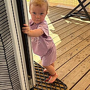 Emma participe au concours pour gagner de l'argent avec cette photo : ankle_bracelet, baby, barefoot, casual, child, curious, daylight, door_frame, home, mat, outdoor, person, playful, portrait, purple_clothing, standing, summer, sunlight, toddler, wooden_deck