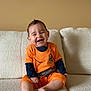 Sebástian Brown joined the competition — help win amazing prizes! baby, child, smiling, laughing, orange_clothing, sitting, couch, indoor, happy, cute, portrait, young_child, infant, furniture, cozy, casual_clothing, shorts, long_sleeve, human, one_person