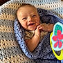 Camden is registered to the contest to win money with this photo: baby, smiling, crocheted_blanket, blue, white, toy, butterfly, infant, cozy, happy, wrapped, cute, hands, indoor, portrait, child, closeup, playful, colorful, soft