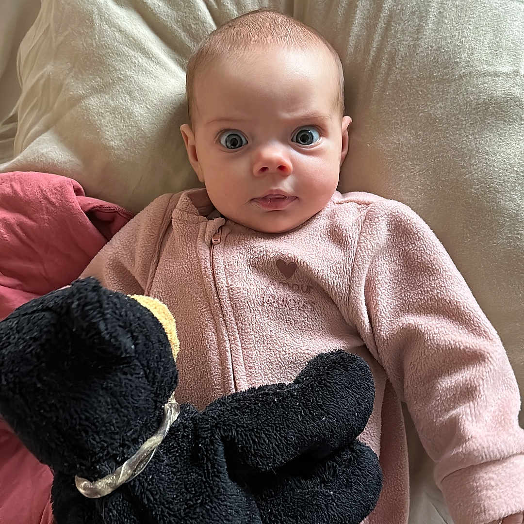 Jade participe au concours pour gagner de l'argent avec cette photo : baby, bed, black_plush_toy, blanket, child, cozy, cuddly, cute, expression, indoor, infant, lying_down, person, pillow, pink_onesie, portrait, sleepwear, soft_texture, stuffed_animal, wide_eyes