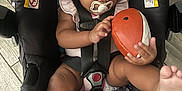 Cherish is registered to the contest to win money with this photo: baby, car_seat, pacifier, toy, football, curly_hair, infant, child, indoors, flooring, colorful, pattern, sitting, legs, hands, face, clothing, straps, safety, playful
