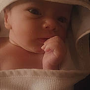 Maldikai is registered to the contest to win money with this photo: baby, child, closeup, cute, expression, face, hand, hooded_towel, indoors, infant, newborn, peaceful, portrait, resting, skin, sleepy, soft_texture, towel, warm_lighting, wrapped