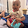 baby, bed, bedroom, child, clothing, curly_hair, door, elephant_toy, expression, feet, fire_truck, happy, indoor, infant, open_mouth, person, play, shirt, sitting, toy
