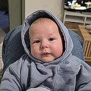 Timiarii participe au concours pour gagner de l'argent avec cette photo : baby, hoodie, blanket, indoor, child, face, hands, seated, person, television, furniture, living_room, cozy, casual_clothing, blue, soft_texture, curious, young_child, portrait, home