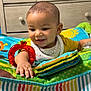 baby, child, toys, play_mat, colorful, happy, smiling, indoor, furniture, dresser, clothing, bib, hand, face, head, infant, cute, expression, room, playtime