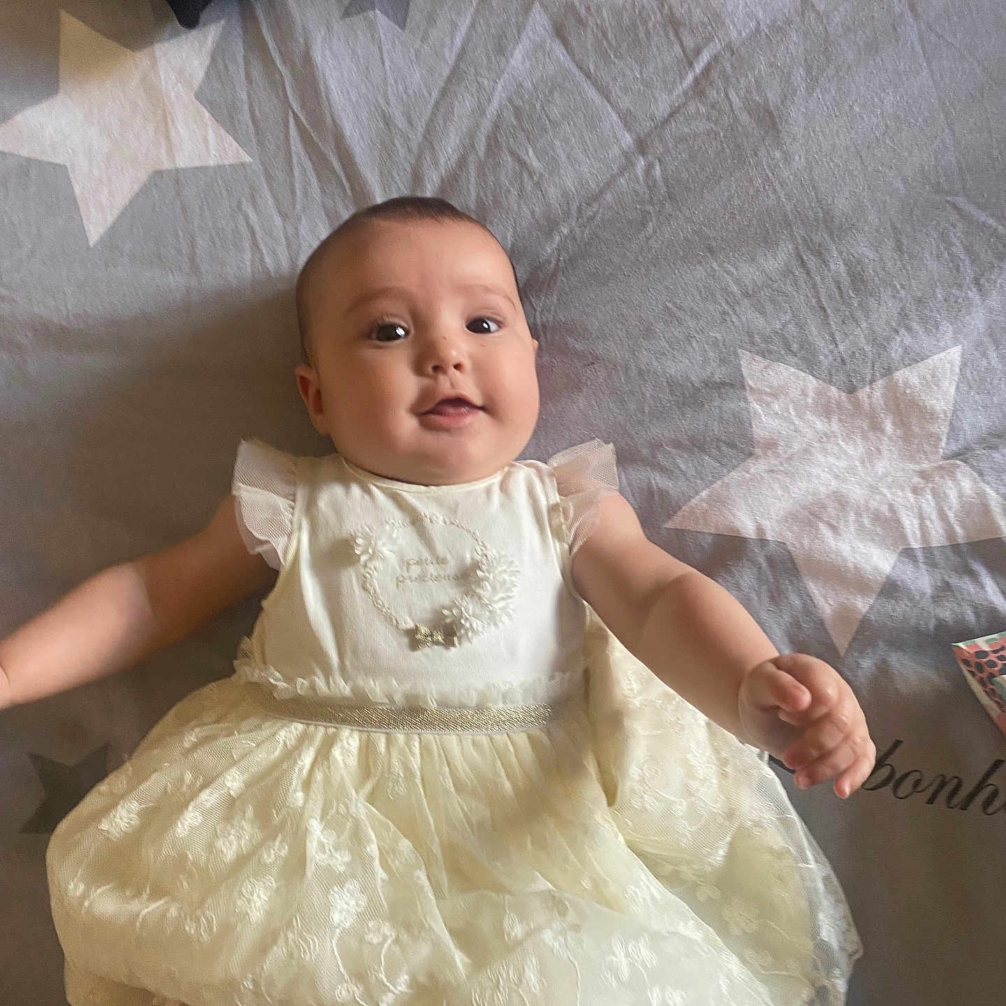Héloïse a rejoint le concours — aidez-le/la à gagner de superbes lots ! arms, baby, bedspread, child, cute, dress, fabric, face, happy, indoors, infant, lace, laying_down, person, pillow, smiling, soft, star_pattern, textile, young