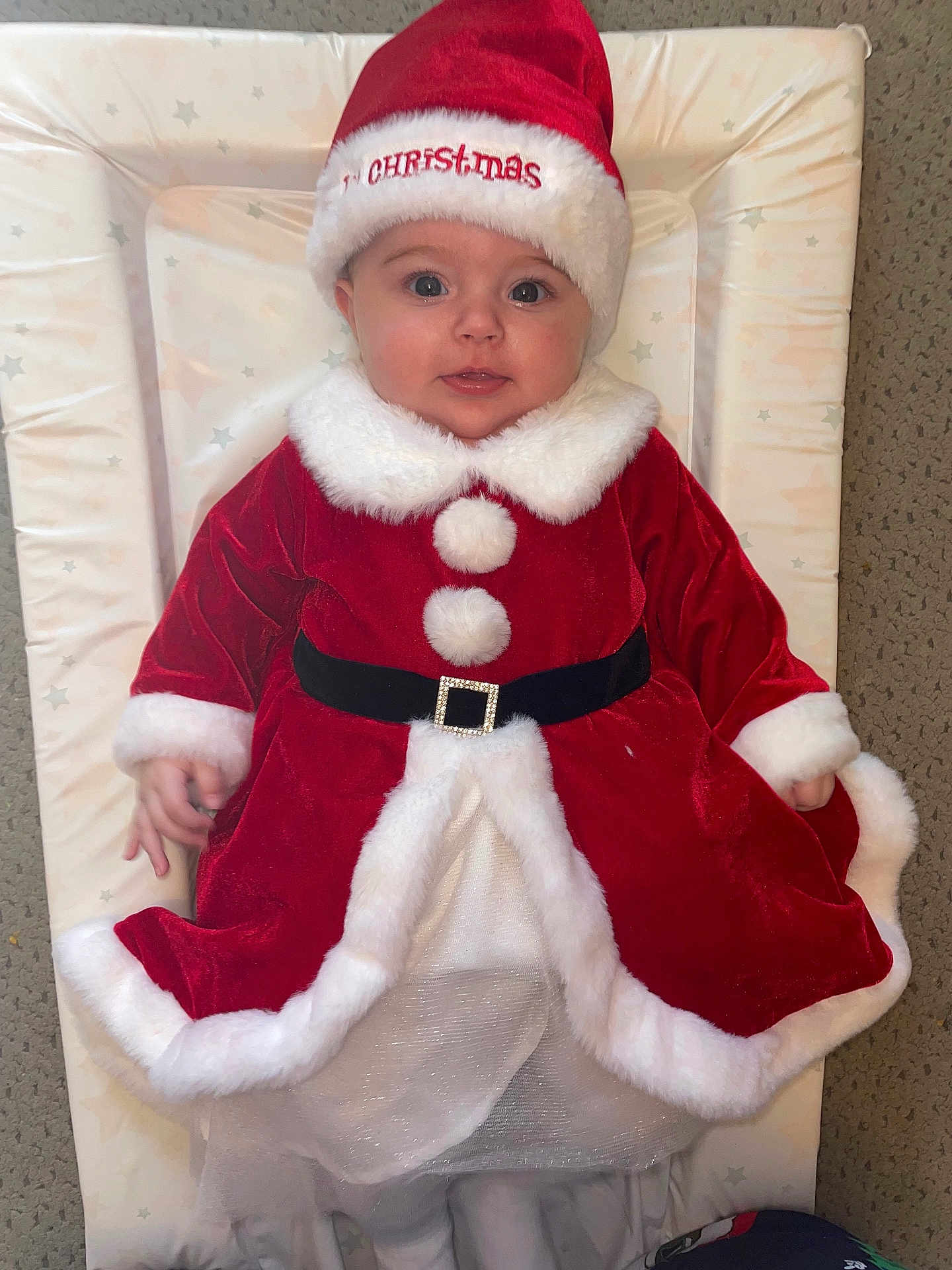 Freya joined the competition — help win amazing prizes! baby, infant, christmas_outfit, santa_hat, red_dress, white_fur_trim, cute, holiday, festive, smiling, lying_down, changing_pad, indoor, carpet, child, portrait, holiday_season, winter_clothing, adorable, young_child