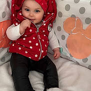 Kaylia participe au concours pour gagner de l'argent avec cette photo : baby, child, red_vest, polka_dots, headband, black_pants, white_socks, blanket, cushions, minnie_mouse, indoor, smiling, seated, cute, portrait, soft_lighting, baby_clothing, infant, playful, cozy