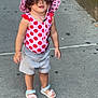 toddler, child, sidewalk, hat, pink, polka_dot, swimsuit, curly_hair, sandals, outdoor, urban, person, concrete, summer, cute, fashion, playful, young_child, standing, daytime