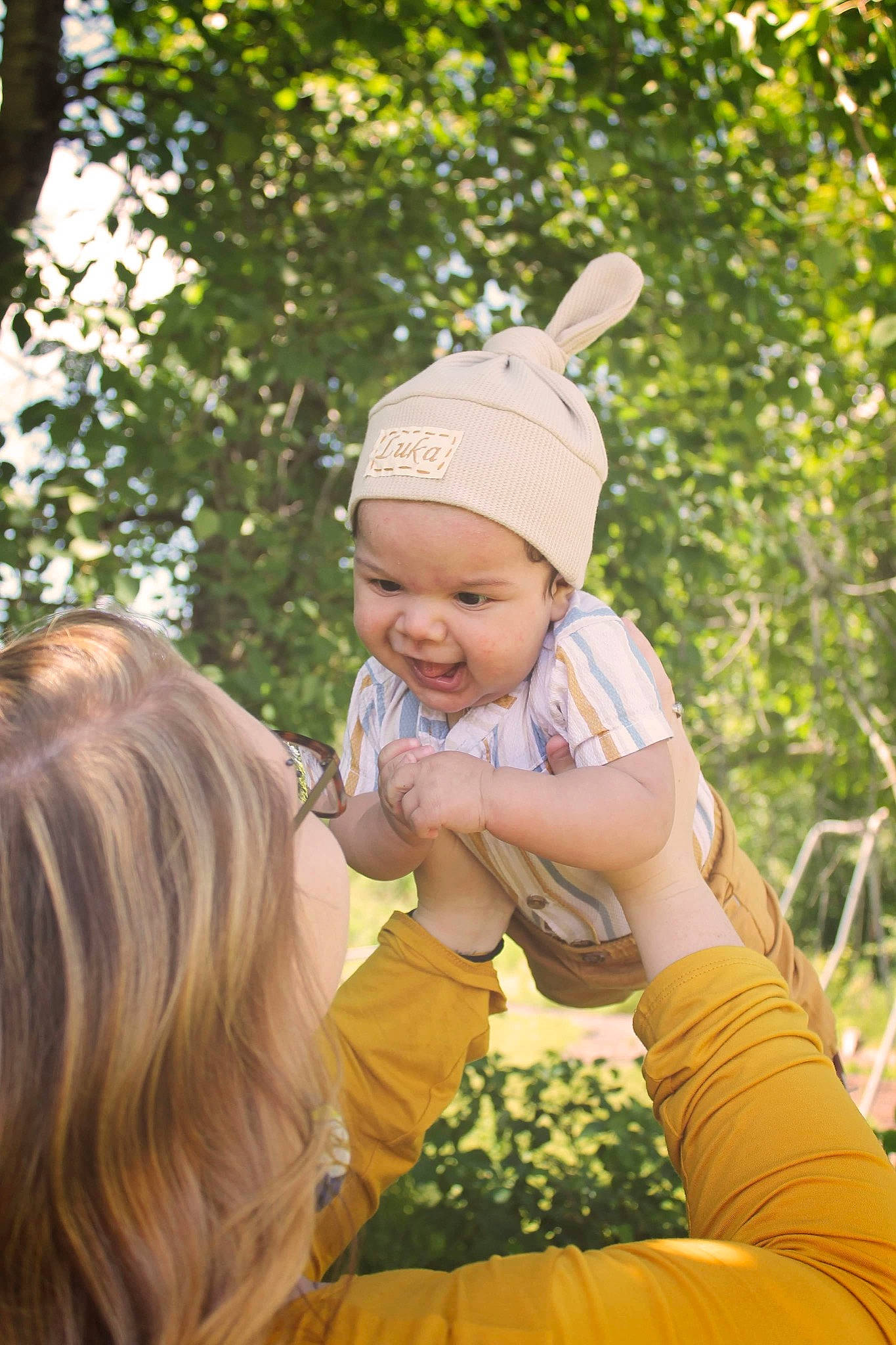 Luka is registered to the contest to win money with this photo: baby, baby_toddler_clothing, botany, cap, child, finger, fun, gesture, grass, hand, happy, headwear, leaf, leisure, mammal, people_in_nature, person, plant, recreation, sunlight
