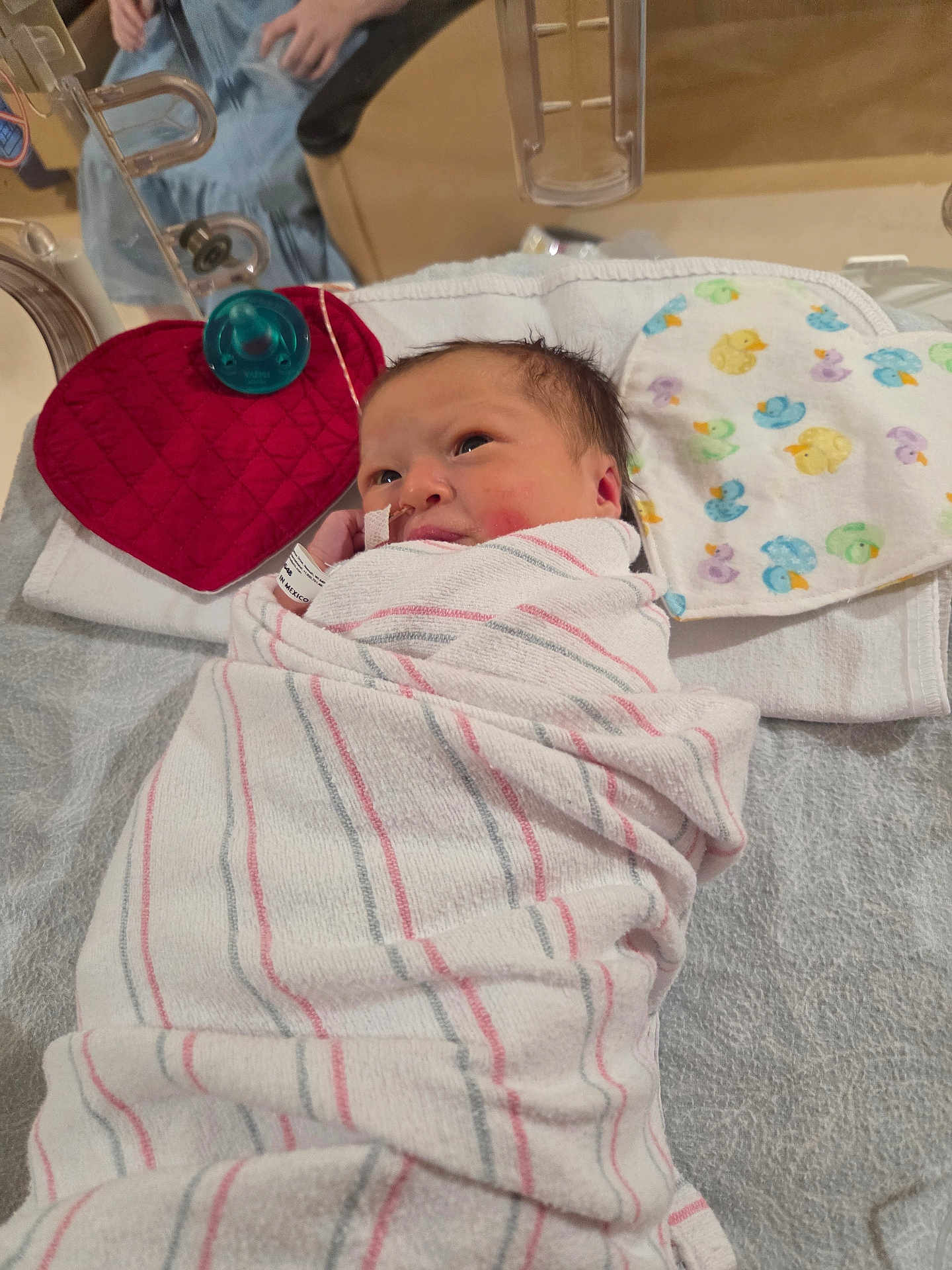 Mariska joined the competition — help win amazing prizes! newborn, baby, hospital, blanket, swaddled, face, infant, medical, nasal_tube, bed, cloth, pattern, duck, red, heart, person, lying_down, cute, healthcare, babycare