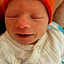 newborn, baby, infant, orange_hat, white_onesie, blanket, closeup, face, sleeping, smiling, cute, soft_texture, indoor, portrait, child, newborn_clothing, baby_fashion, baby_hat, baby_blanket, human