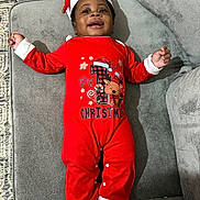 Uzziah joined the competition — help win amazing prizes! baby, child, smiling, christmas, holiday, onesie, red_clothing, hat, socks, couch, furniture, indoors, happy, portrait, infant, cute, cozy, celebration, festive, person