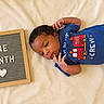Kasei joined the competition — help win amazing prizes! baby, blanket, blue_clothing, celebration, child, cute, fire_truck, hands, heart, indoor, infant, laying_down, milestone, newborn, onesie, peaceful, portrait, sign, soft_texture, text