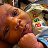baby, infant, close_up, face, hand, clothing, cartoon_characters, mickey_mouse, donald_duck, pluto, colorful_text, skin, eyes, fist, cute, portrait, soft_lighting, indoors, child, young