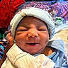 newborn, baby, smiling, face, hat, blanket, hand, person, indoors, clothing, portrait, sleepwear, cute, infant, cozy, expression, human, soft, wrapped, closeup