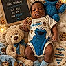 baby, infant, one_month, cookie_monster, stuffed_toy, teddy_bear, cookie, blanket, blue_socks, onesie, letter_board, soft_toy, child, cute, smiling, cozy, portrait, indoor, baby_clothes, decor