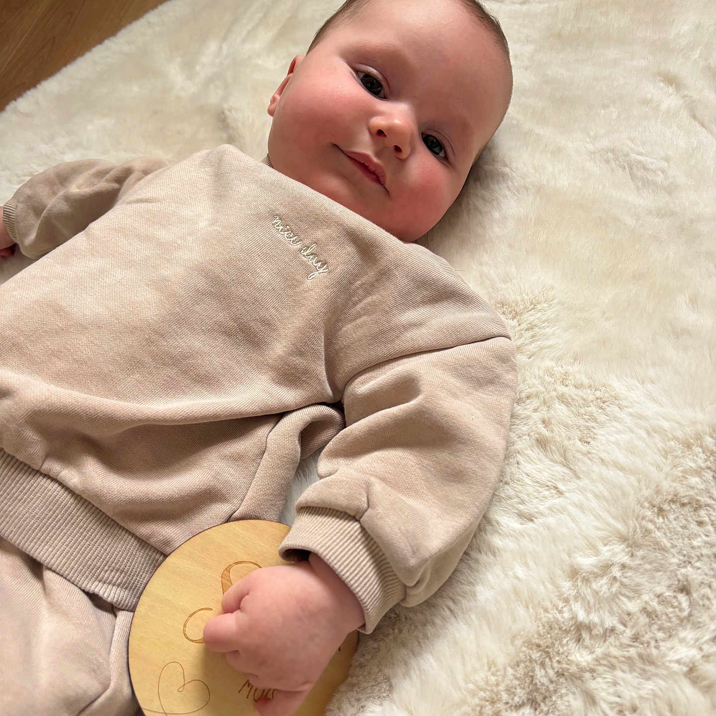 Ethann a rejoint le concours — aidez-le/la à gagner de superbes lots ! baby, child, clothing, cozy, cute, face, floor, fluffy_rug, hand, human, indoor, infant, pants, person, rug, skin, smile, sweatshirt, toy, wooden_toy