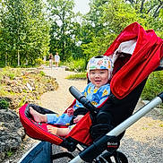 Alex joined the competition — help win amazing prizes! Britax, baby, child, clothing, daytime, family, footwear, greenery, happy, helmet, nature, outdoor, park, path, person, rocks, smile, stroller, sunlight, trees
