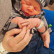 Hunter is registered to the contest to win money with this photo: newborn, baby, infant, hat, clothing, plaid_shirt, jeans, hand, holding, hospital_wristband, sleeping, cute, tender, peaceful, portrait, indoor, person, newborn_baby, closeup, family