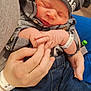 newborn, baby, infant, hat, clothing, plaid_shirt, jeans, hand, holding, hospital_wristband, sleeping, cute, tender, peaceful, portrait, indoor, person, newborn_baby, closeup, family