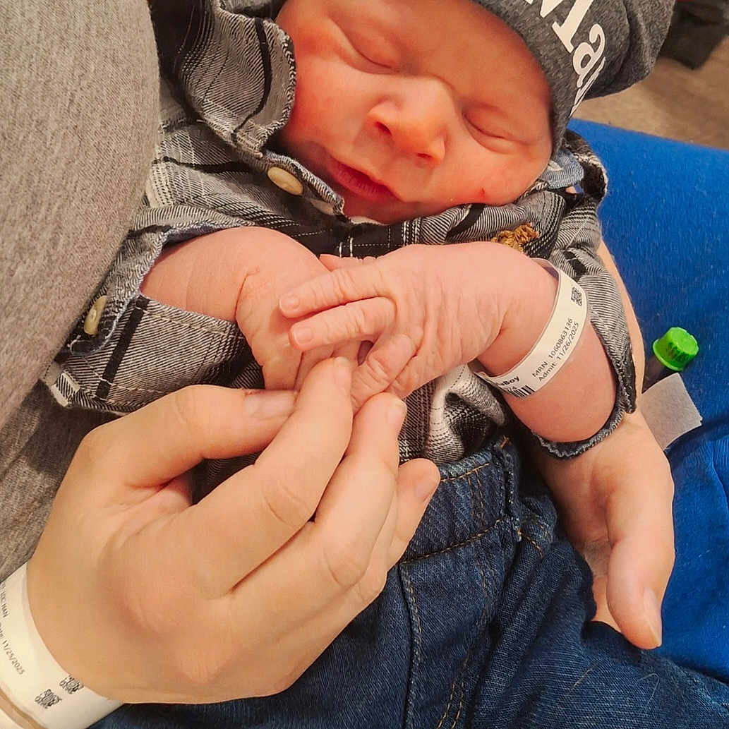 Hunter is registered to the contest to win money with this photo: baby, closeup, clothing, cute, family, hand, hat, holding, hospital_wristband, indoor, infant, jeans, newborn, newborn_baby, peaceful, person, plaid_shirt, portrait, sleeping, tender