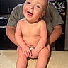 Grayson is registered to the contest to win money with this photo: baby, smiling, drool, countertop, kitchen, adult, holding, cabinet, microwave, fridge, magnets, photos, person, shirt, indoor, happy, skin, face, child, diaper