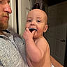 Grayson is registered to the contest to win money with this photo: baby, man, diaper, indoor, holding, beard, shirt, door, hand, face, skin, curious, happy, child, person, parent, home, infant, chewing, object