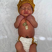 Richard is registered to the contest to win money with this photo: newborn, baby, sleeping, crown, knitted_clothing, diaper_cover, necklace, gold_jewelry, soft_blanket, infant, cute, peaceful, handmade, portrait, lying_down, skin, headwear, small_hands, small_feet, indoors