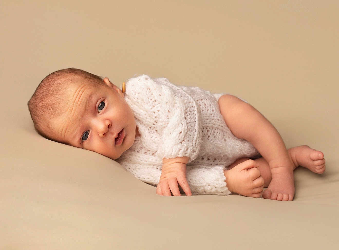 Elyo a rejoint le concours — aidez-le/la à gagner de superbes lots ! baby, newborn, infant, knitted_clothing, lying_down, beige_background, soft_texture, cute, small_hands, small_feet, portrait, human, child, sleepy, cozy, studio_photo, closeup, peaceful, skin, expression
