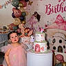 Mia is registered to the contest to win money with this photo: toddler, child, birthday, cake, balloons, pink_dress, party, princess, decorations, gift, dollhouse, portrait, standing, indoors, celebration, face, dark_hair, frilly_outfit, social_media, photograph
