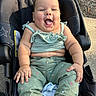 baby, child, infant, smiling, happy, sitting, car_seat, outdoor, portrait, face, open_mouth, green_clothing, romper, pants, pink_shoe, sunlight, playground, pavement, star_pattern, photography