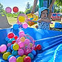Théo participe au concours pour gagner de l'argent avec cette photo : toddler, child, hat, blue_hat, outdoor, daylight, balls, colorful_balls, net, pink_net, basket, adult, person, grass, tree, car, play, sunny, toy, summer