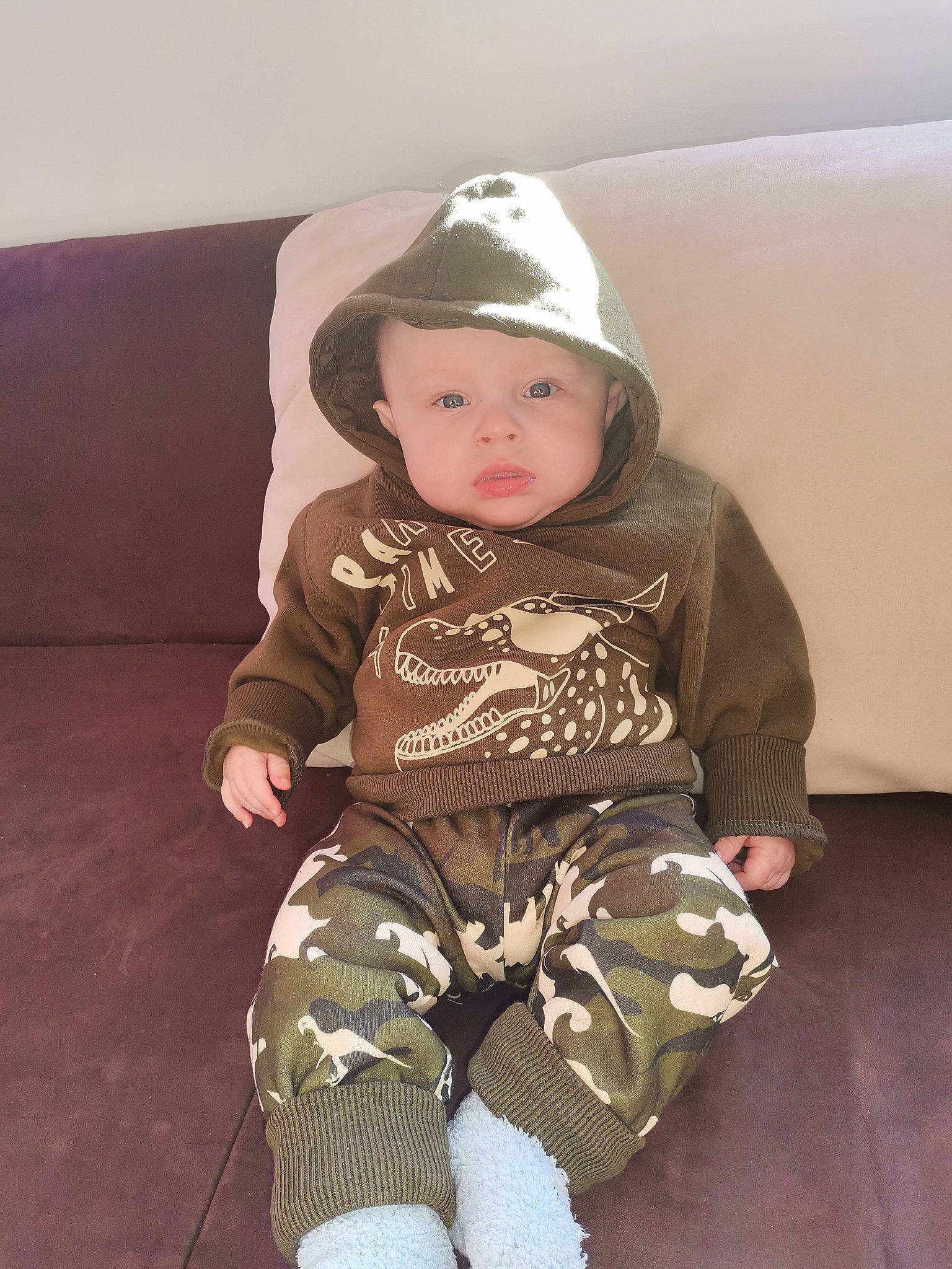 Tiziano participe au concours pour gagner de l'argent avec cette photo : arm, baby, baby_toddler_clothing, cap, cheek, comfort, eye, headwear, human_body, human_leg, knee, leg, pattern, person, personal_protective_equipment, sitting, skin, sleeve, sock, t_shirt