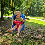 Aries joined the competition — help win amazing prizes! toddler, child, swing, outdoor, playground, trees, greenery, grass, sunlight, nature, smiling, blonde_hair, curly_hair, blue_swing, red_swing, barefoot, summer, park, happy, daytime