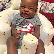 A Donis is registered to the contest to win money with this photo: baby, ball, clothing, couch, cushion, face, football, furniture, happy, head, homedecor, people, person, photography, portrait, sitting, soccer, soccerball, sport, t_shirt