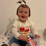 Emy participe au concours pour gagner de l'argent avec cette photo : baby, child, smiling, pigtails, white_shirt, jeans, polka_dot_tights, brown_shoes, bottle, sitting, star_pattern, cushion, indoor, happy, cute, playful, person, infant, toy, wall