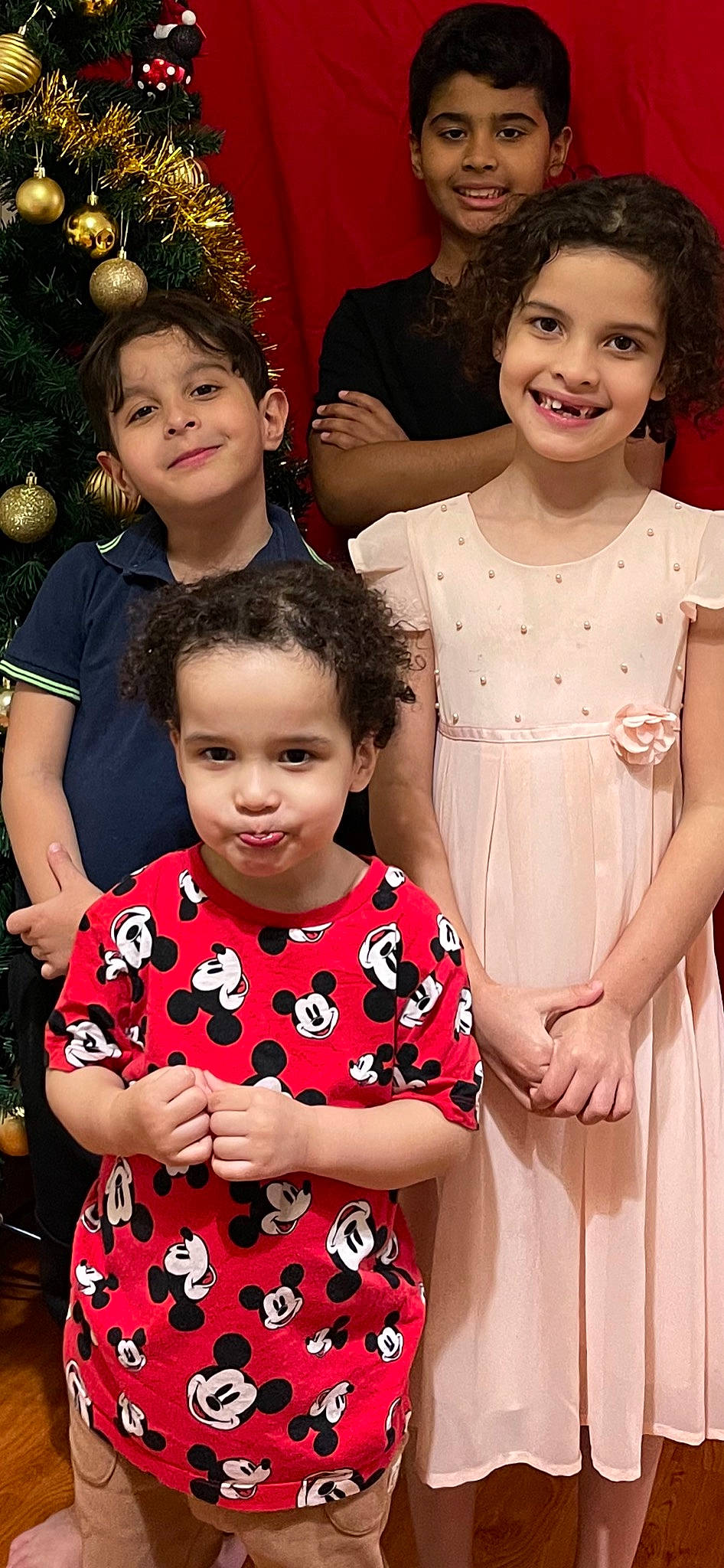 Gustavo is registered to the contest to win money with this photo: face, facial_expression, fashion, fun, hairstyle, happy, head, interaction, joy, one_piece_garment, person, photograph, pink, red, skin, sleeve, smile, social_group, standing, toddler