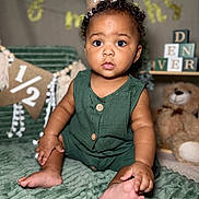 Denver is registered to the contest to win money with this photo: baby, child, party_hat, green_outfit, sitting, blanket, teddy_bear, decorations, milestone, curious, wide_eyes, cute, indoor, portrait, celebration, soft_texture, buttoned_outfit, fuzzy, infant, birthday