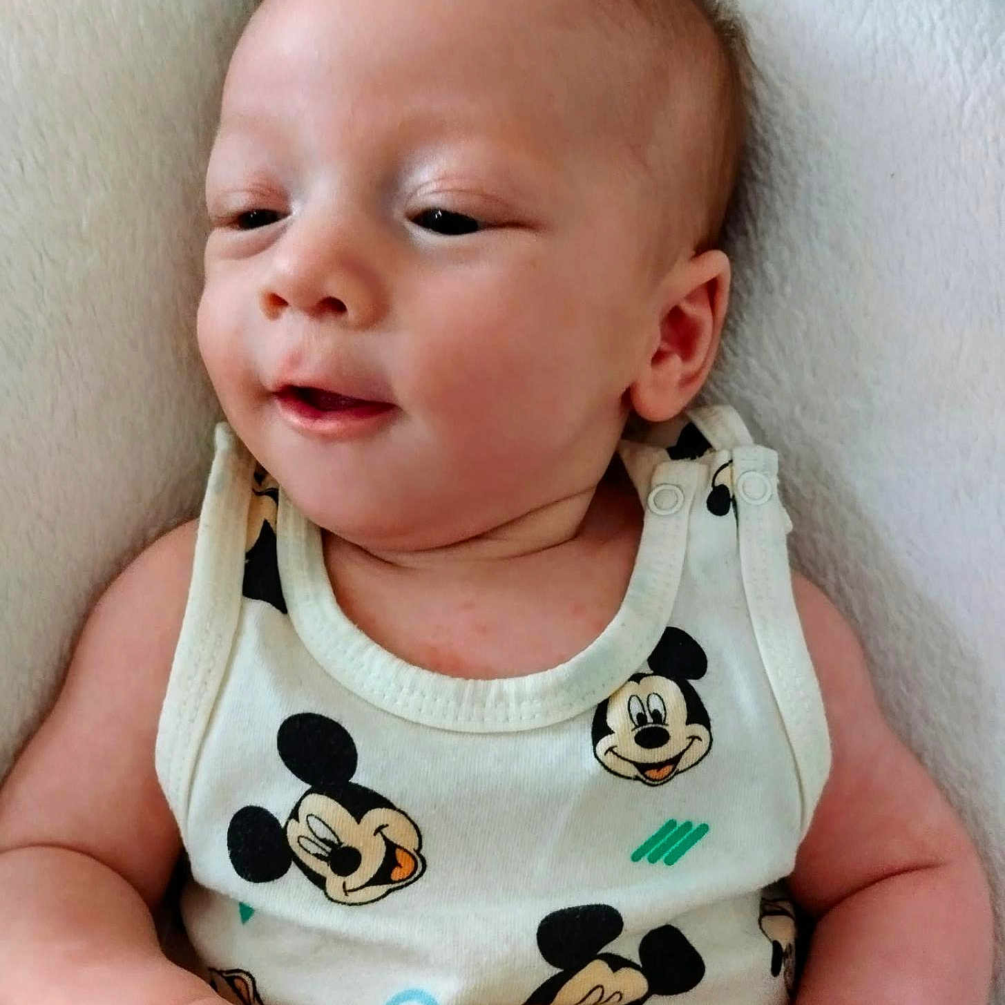 Kamel participe au concours pour gagner de l'argent avec cette photo : baby, infant, child, mickey_mouse, tank_top, clothing, cute, lying_down, white_background, soft_texture, skin, face, expression, hand, arm, person, portrait, closeup, indoors, comfortable